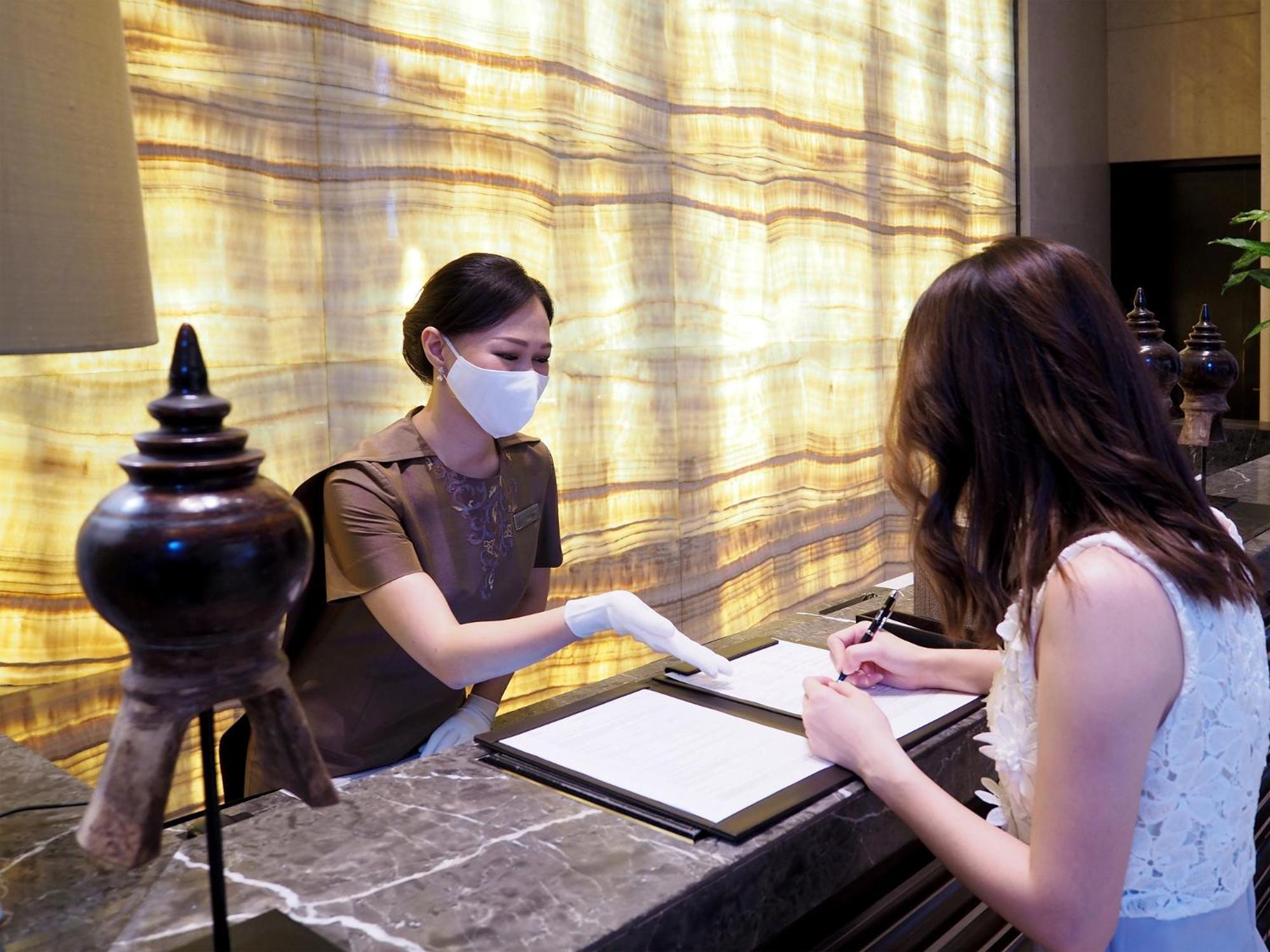 Siam Kempinski Hotel Bangkok Eksteriør bilde A hotel receptionist wearing a face mask